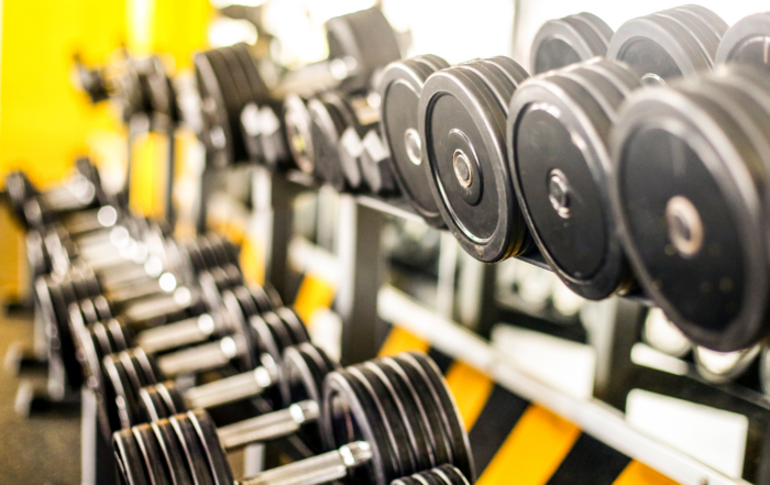 closeup of dumbells in an apartment gym with a yellow wall